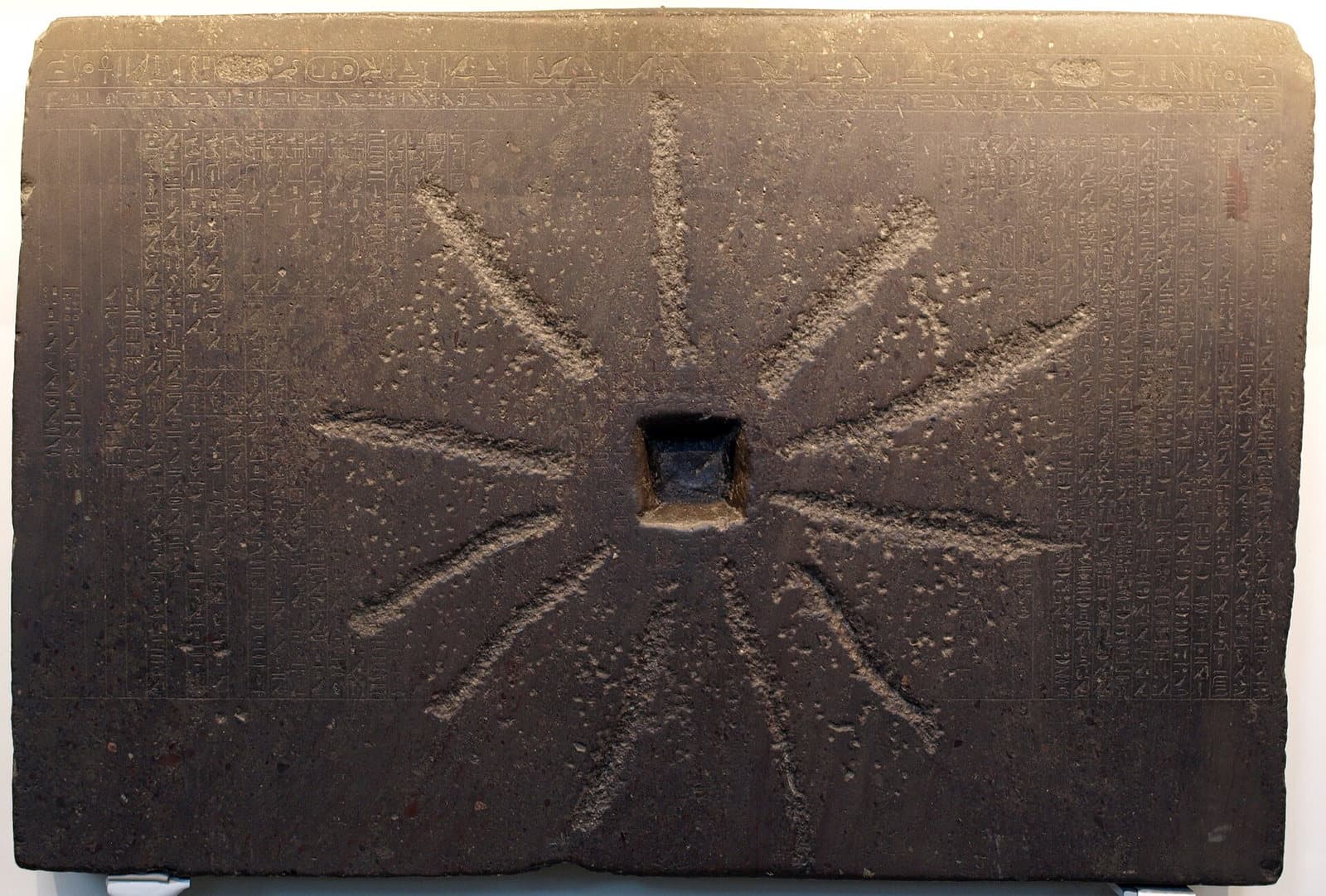 Photographie d'une grande dalle de pierre gravée d'hiéroglyphes, la pierre de Chabaka, exposée au British Museum.