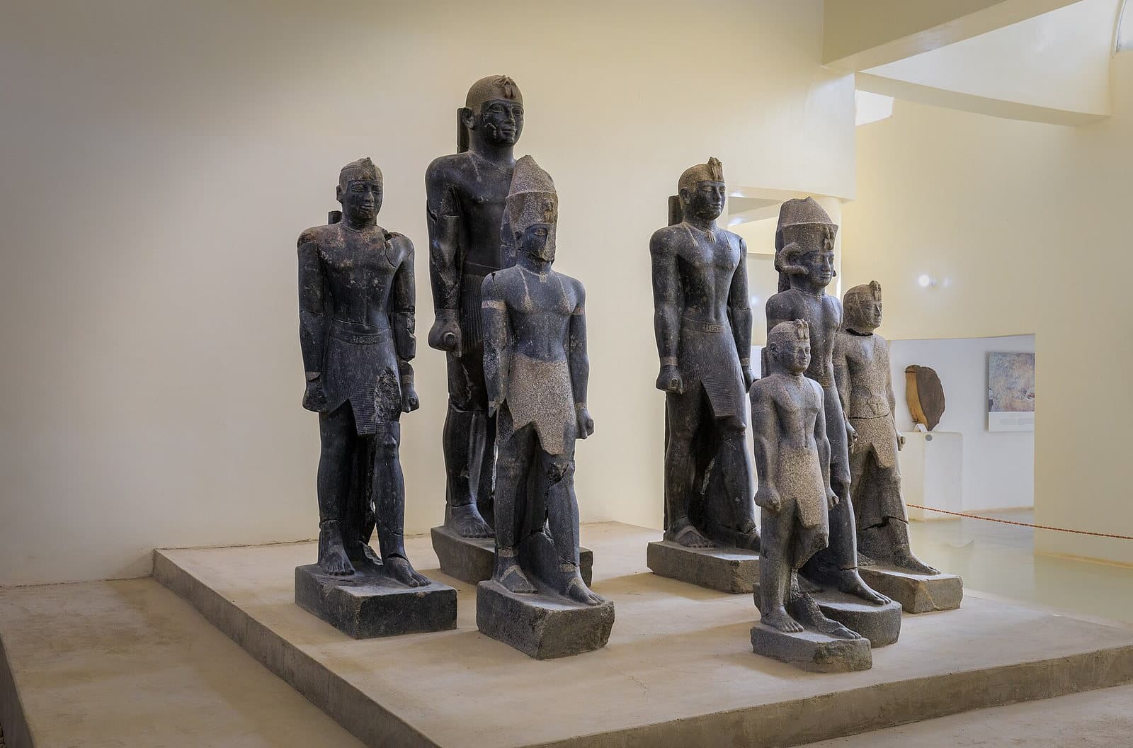 Rangée de sept grandes statues royales de pierre noire, brisées puis reconstituées, exposées au musée de Kerma au Soudan.
