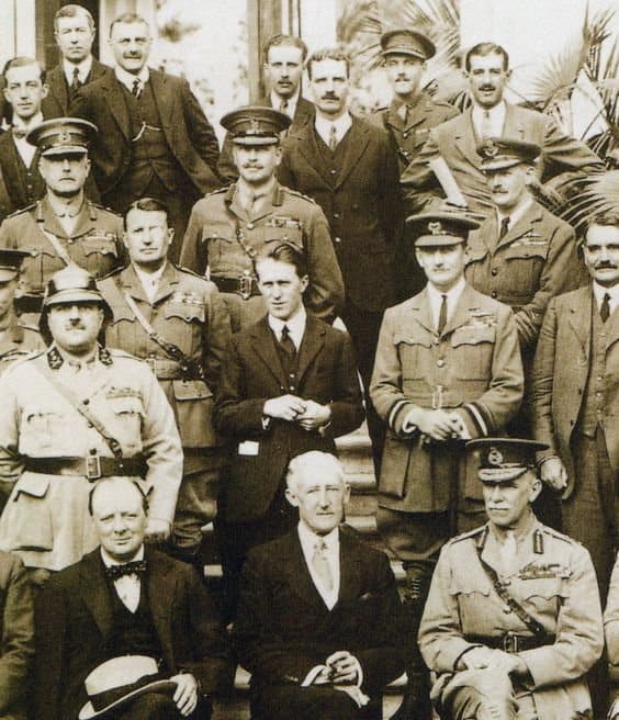 Photographie de groupe en sépia de responsables et officiers britanniques posant sur un perron lors de la conférence du Caire, mars 1921 ; Winston Churchill assis au premier rang.